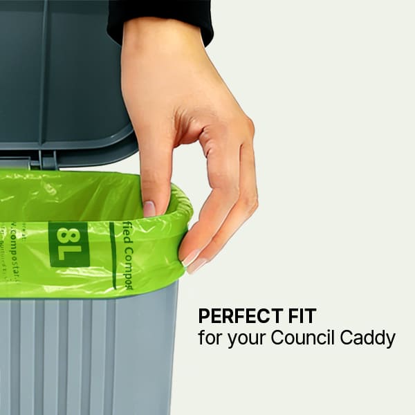 A hand adjusting a green Compostar 8L compostable bag to perfectly fit the rim of a grey local council kitchen caddy.